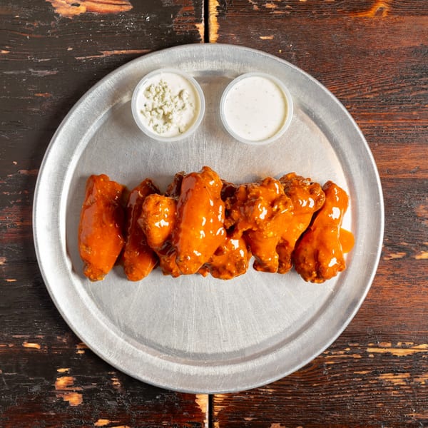 Bambino's Urban Pizzeria's buffalo wings with blue cheese and ranch dipping sauces on a metal tray.