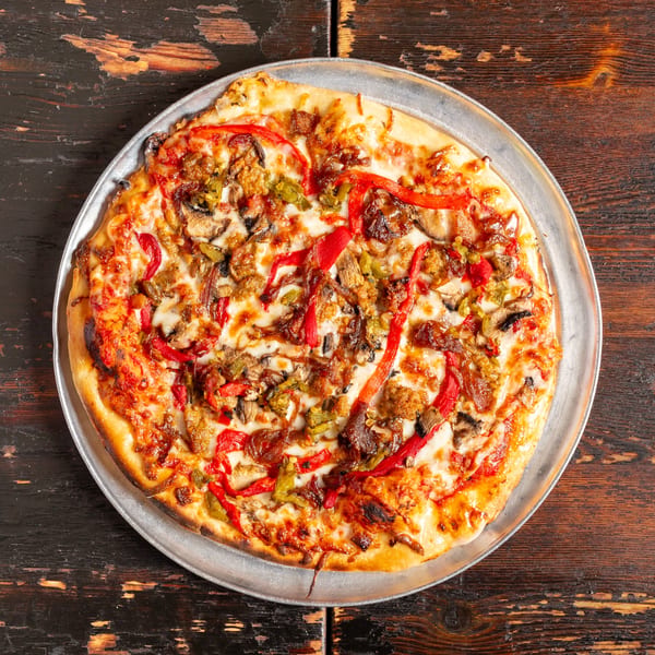 Bambino's Urban Pizzeria's pizza with red peppers, mushrooms, and sausage on a metal pan.