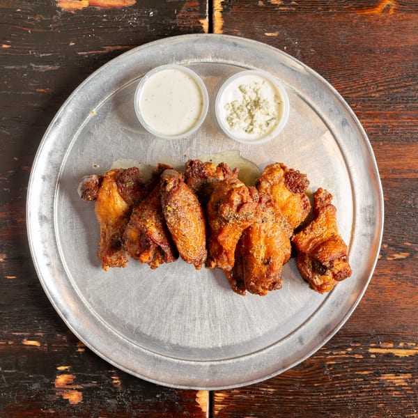 Bambino's Urban Pizzeria's crispy chicken wings with ranch and blue cheese dipping sauces on a metal tray.